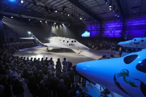 A gauche : le nouveau SpaceShip Two. A droite, un bout du White Knight Two. Au milieu, Richard Branson et sa belle chevelure blonde. Source : http://www.virgingalactic.com/